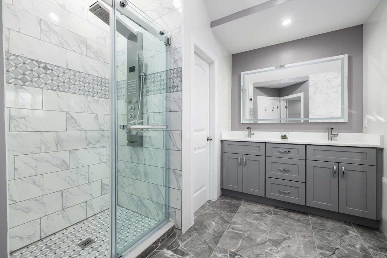 Luxurious modern bathroom featuring grey cabinets and a marble-tiled shower.