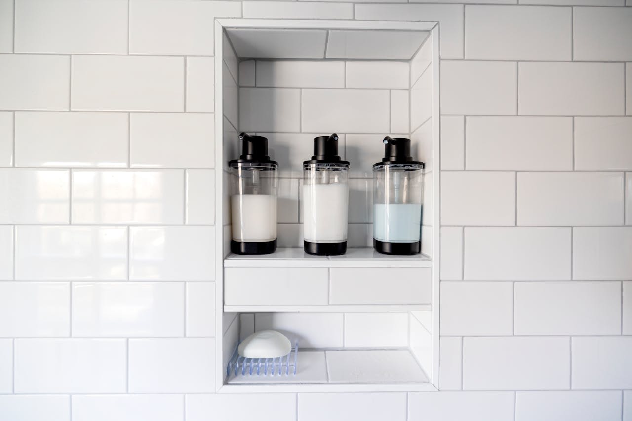 Clean and minimalist bathroom design featuring soap dispensers and white tiles.